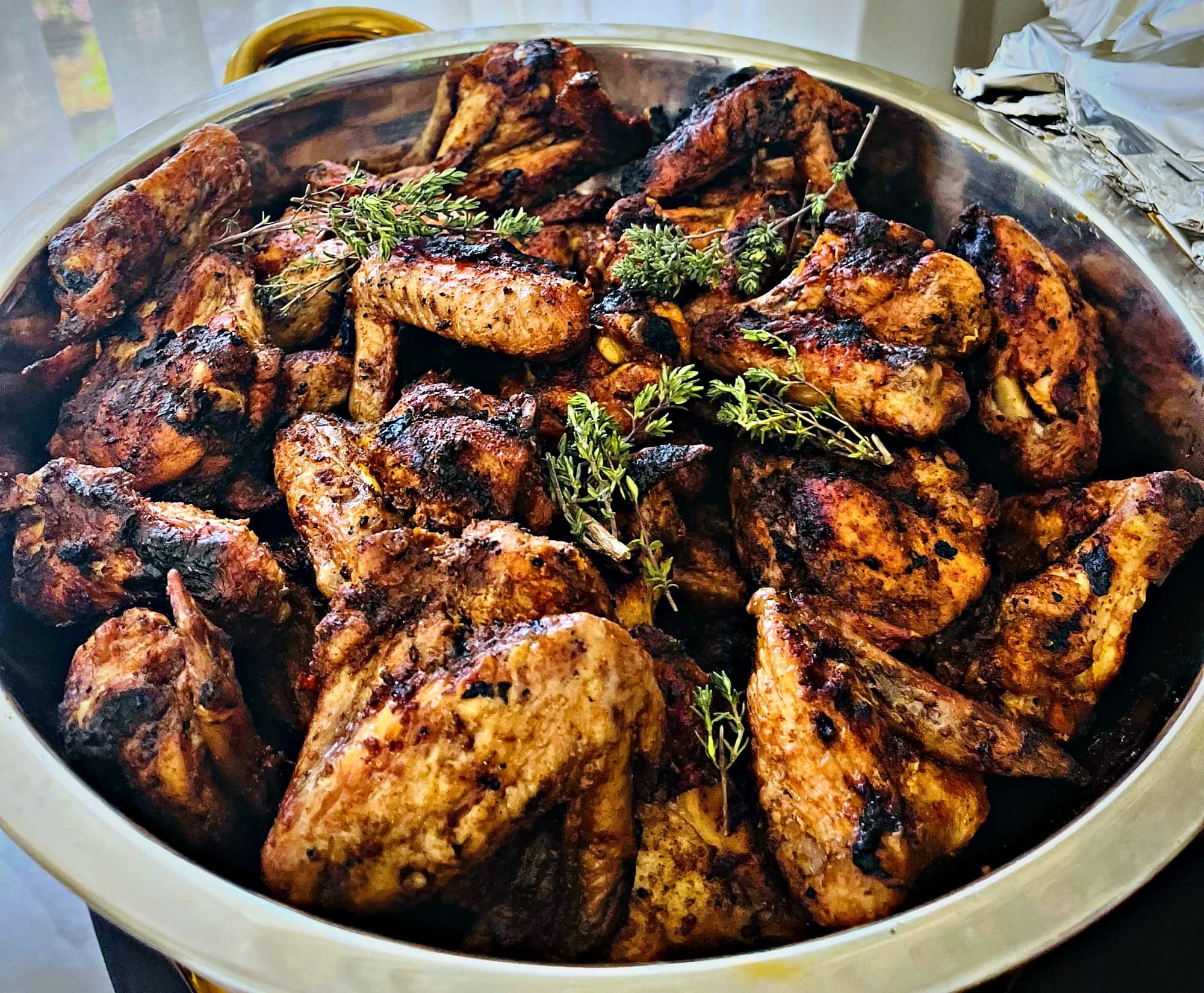 Grilled chicken wings with thyme heaped in a gold-handled pot